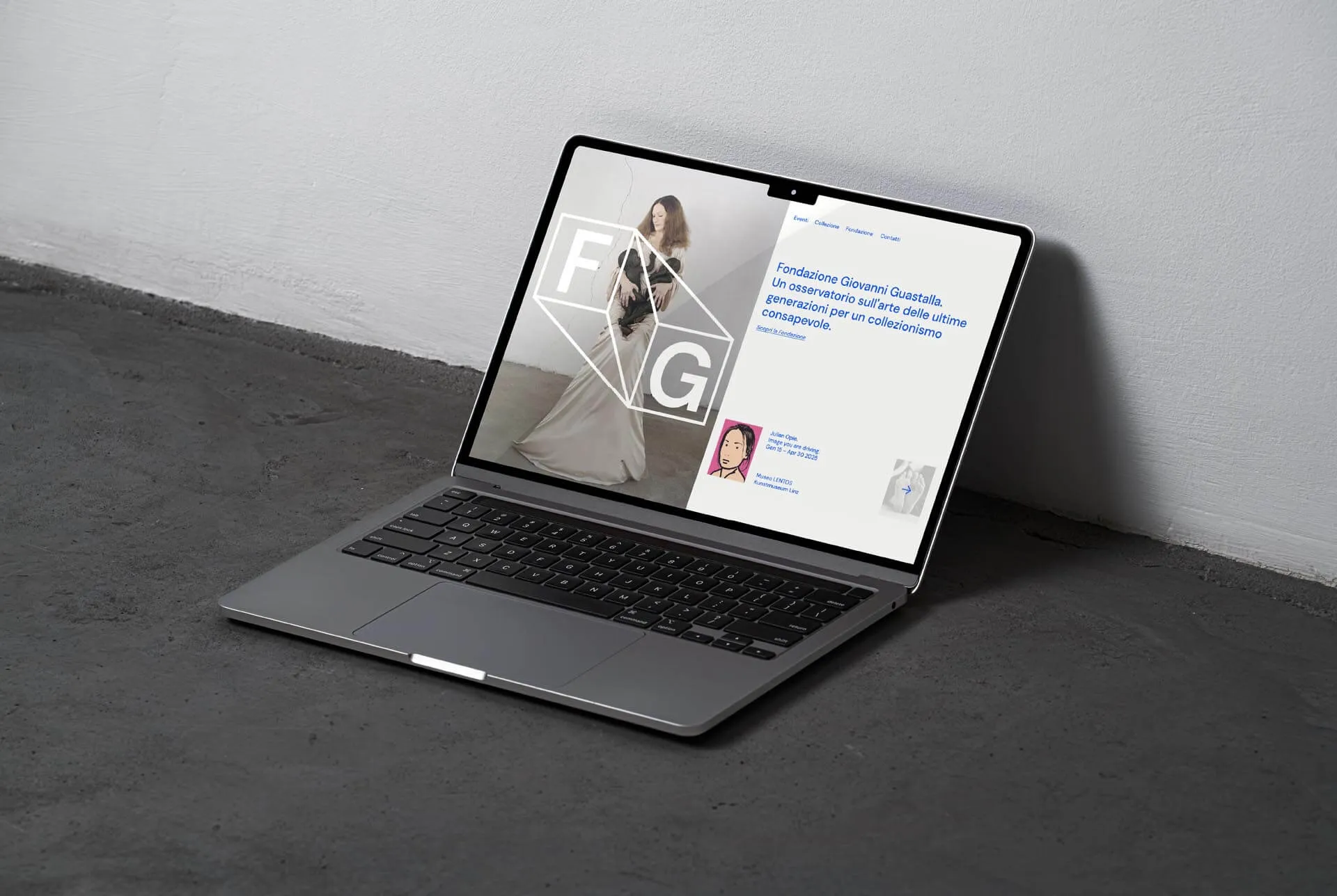 Open laptop on gray surface displaying Fondazione Giovanni Guastalla homepage with a woman in a long dress and text in Italian.