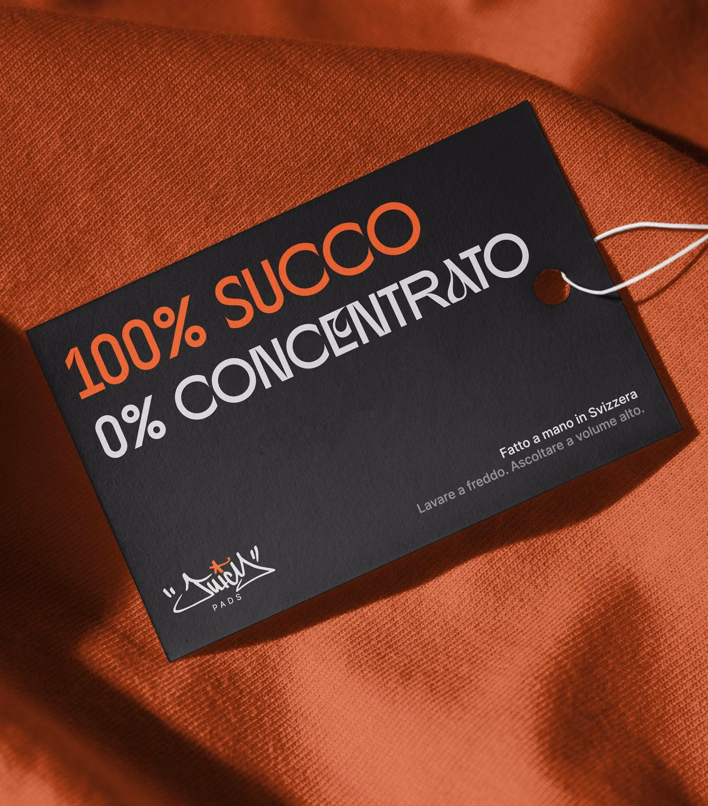 Juicy Pads merch tag on an orange sweatshirt: 100% succo, 0% concentrato