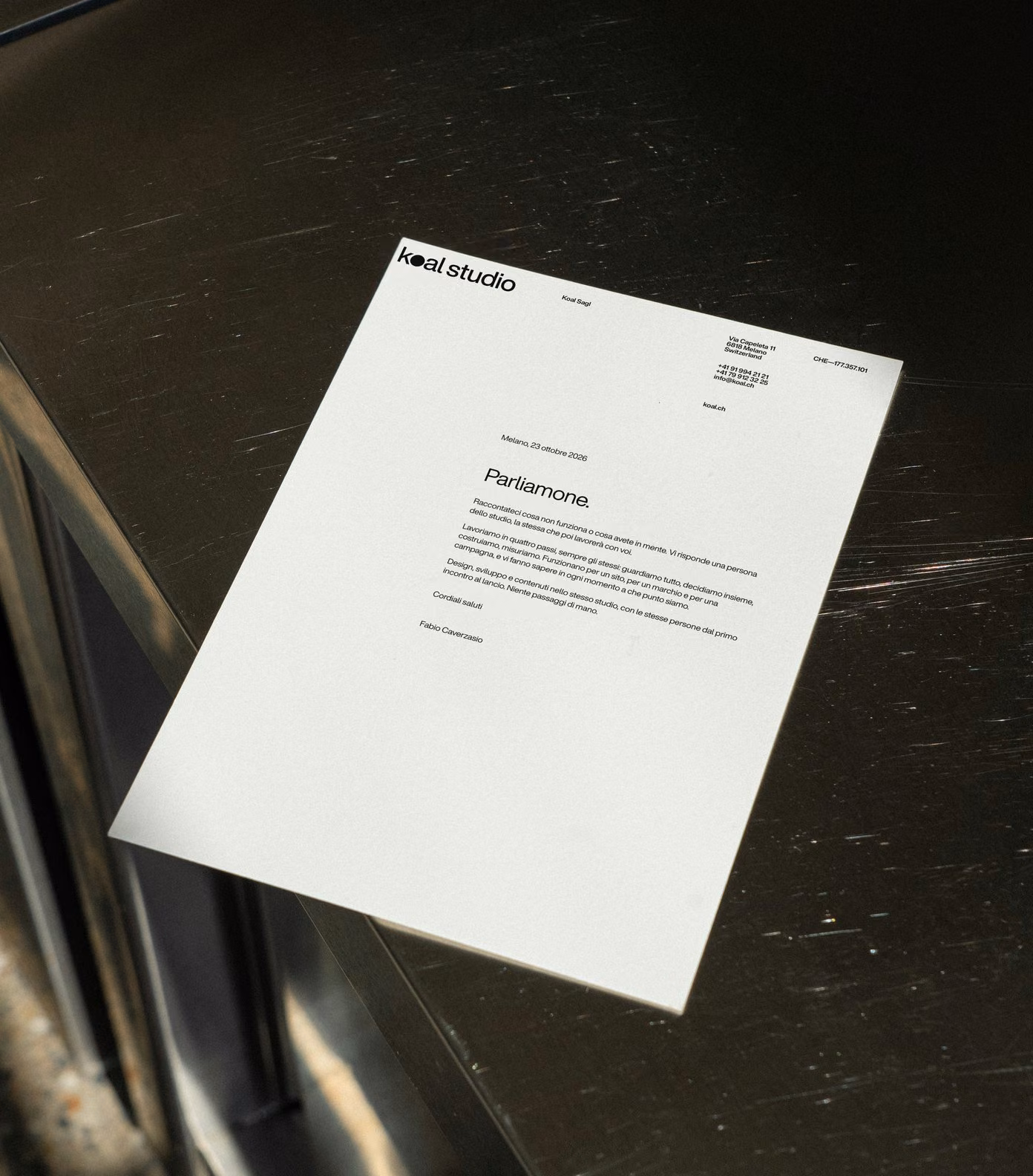 Koal Studio letterhead on a steel counter in the sun: Parliamone