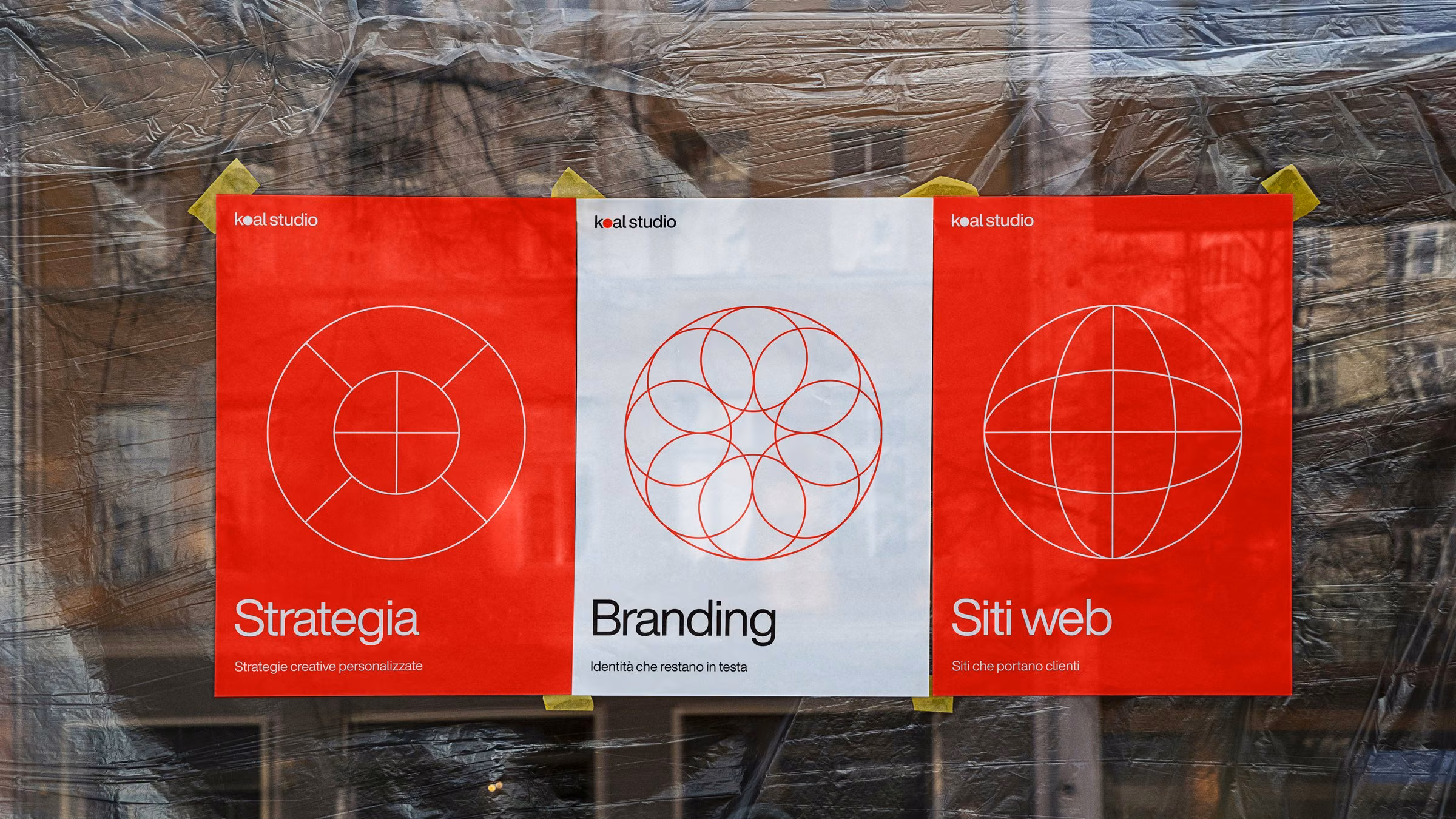 Three Koal Studio posters in a shop window with the service icons: strategy, branding, websites