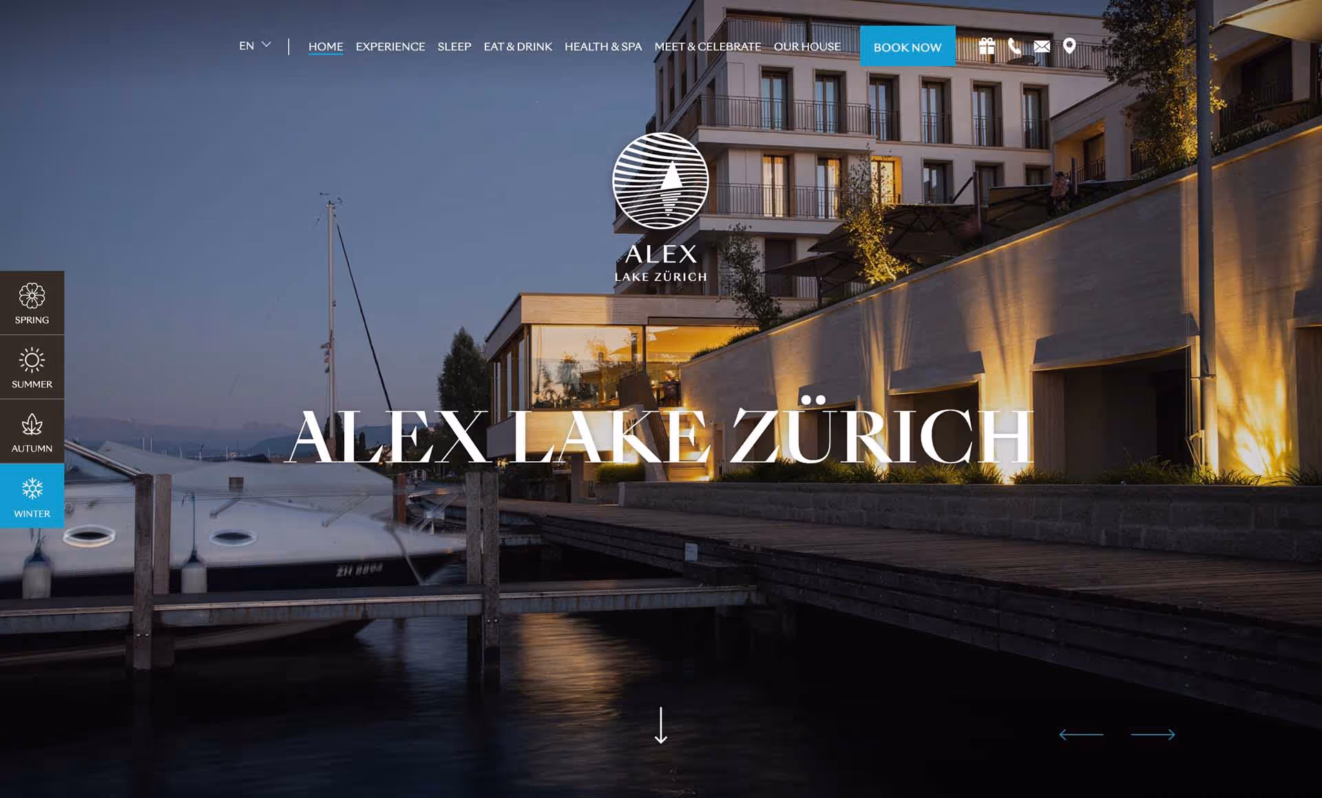 Waterfront hotel building with illuminated facade and docked sailboats at dusk at Alex Lake Zürich.