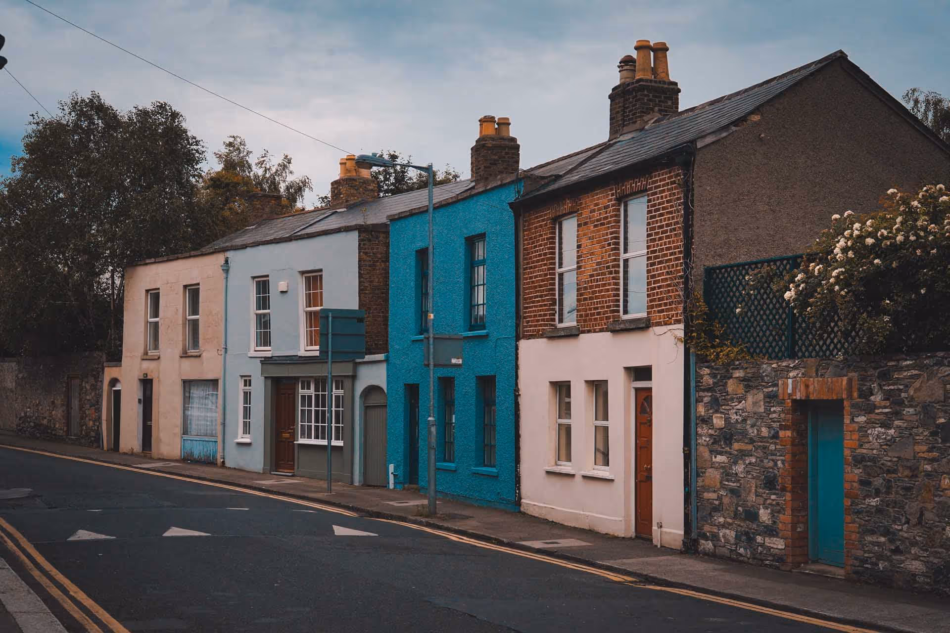 Row of colorful terraced houses along a curved street under an overcast sky.