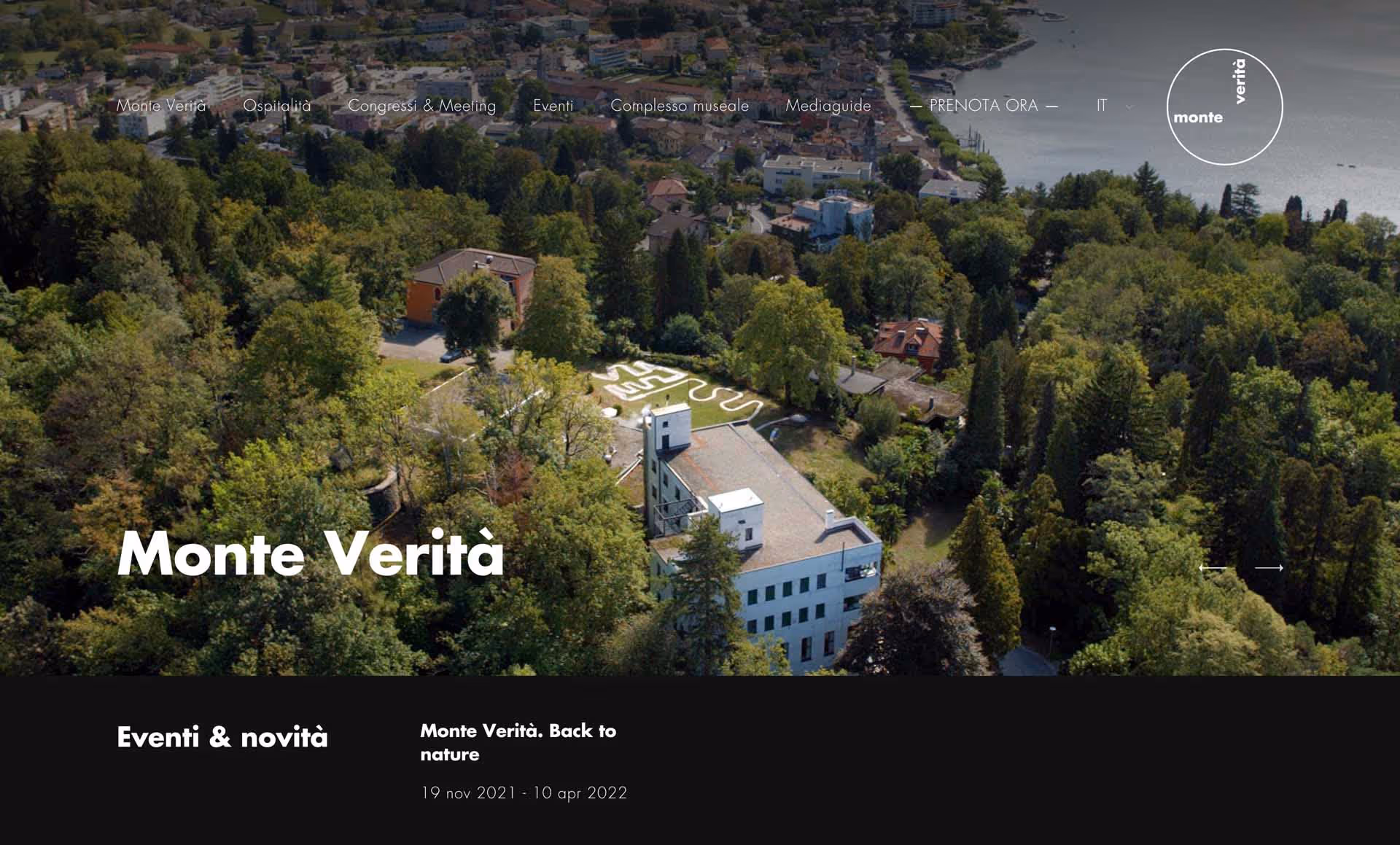 Aerial view of Monte Verità with dense greenery, buildings, and a lake in the background.