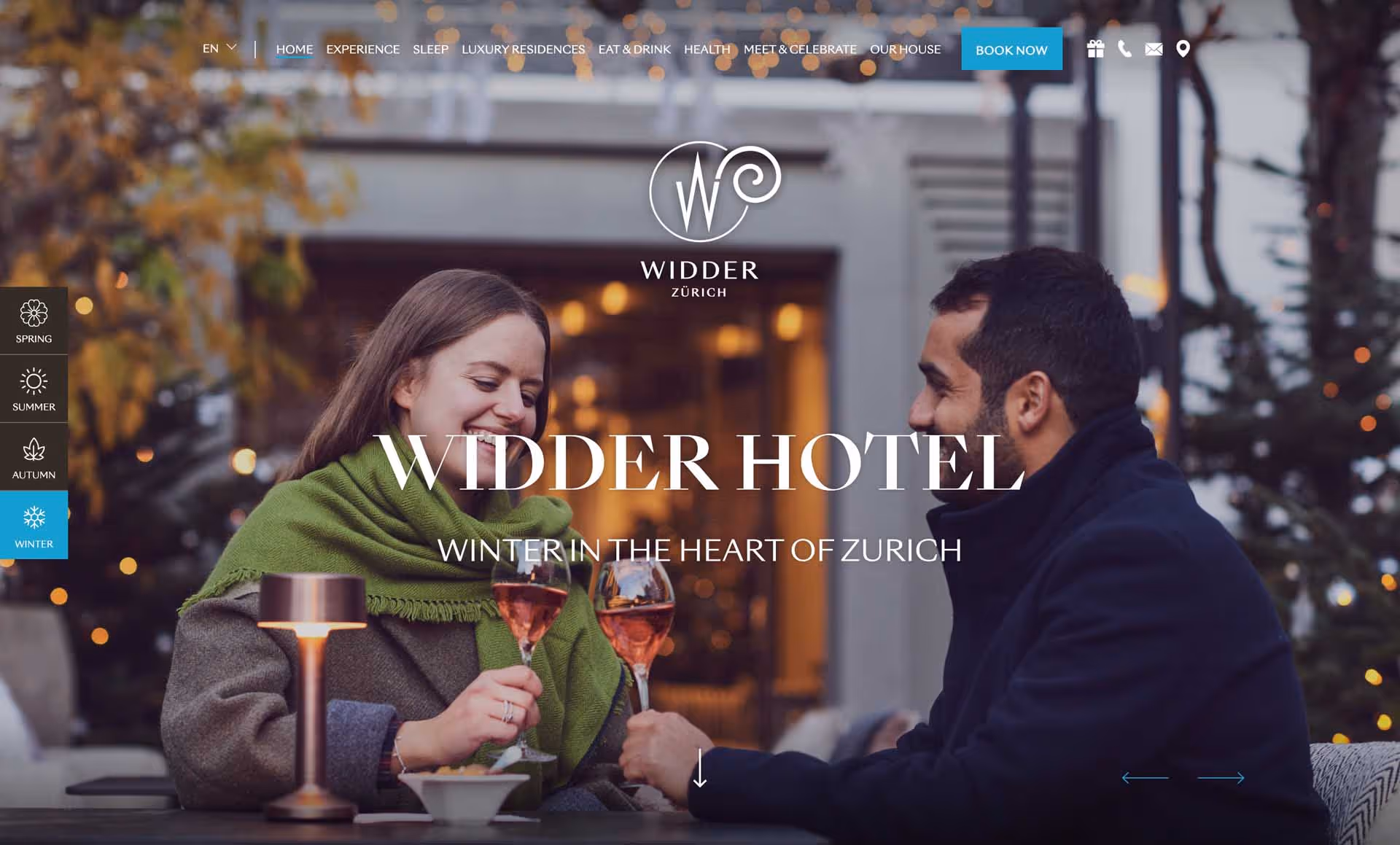 A smiling woman and man clinking glasses of rose wine at an outdoor table in winter at Widder Hotel Zurich.