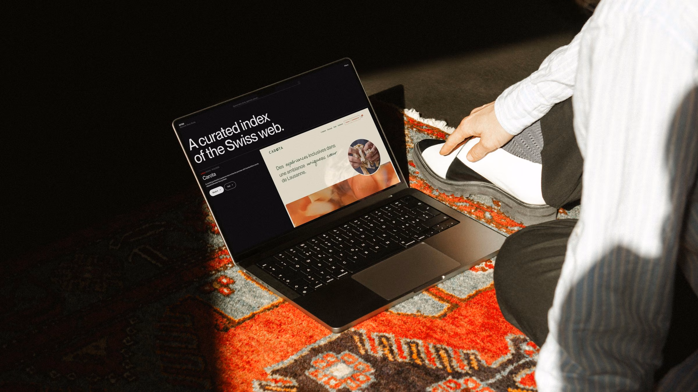 The Sited home page on a laptop on a Persian rug
