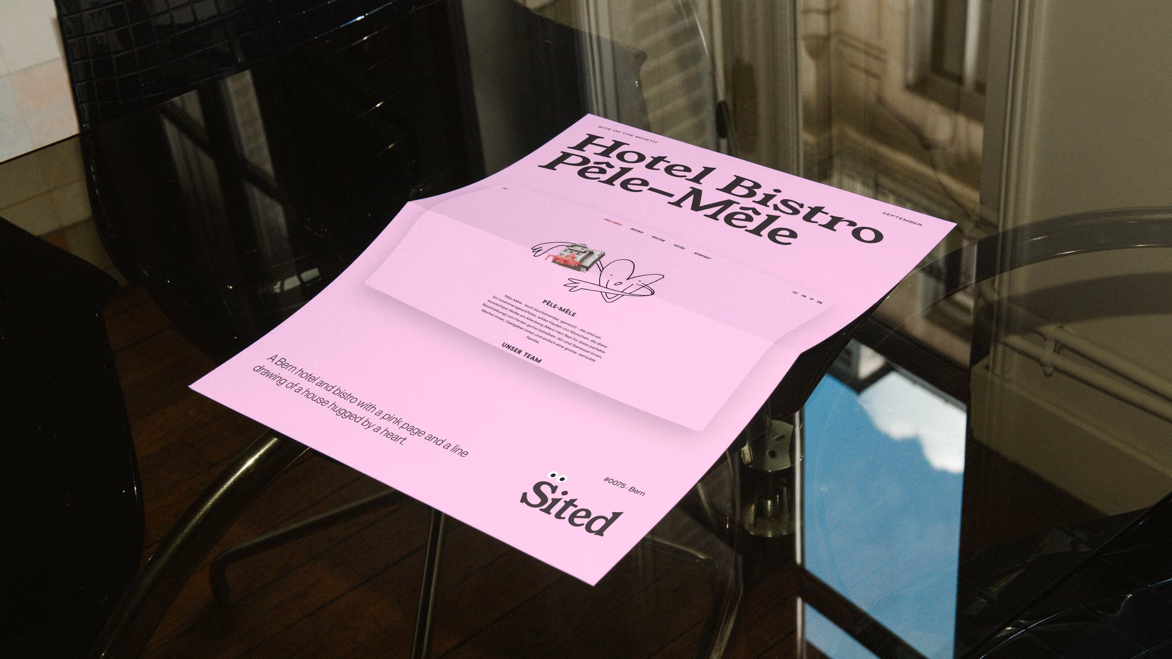 Site of the month poster on a glass table: Hotel Bistro Pêle-Mêle on pink
