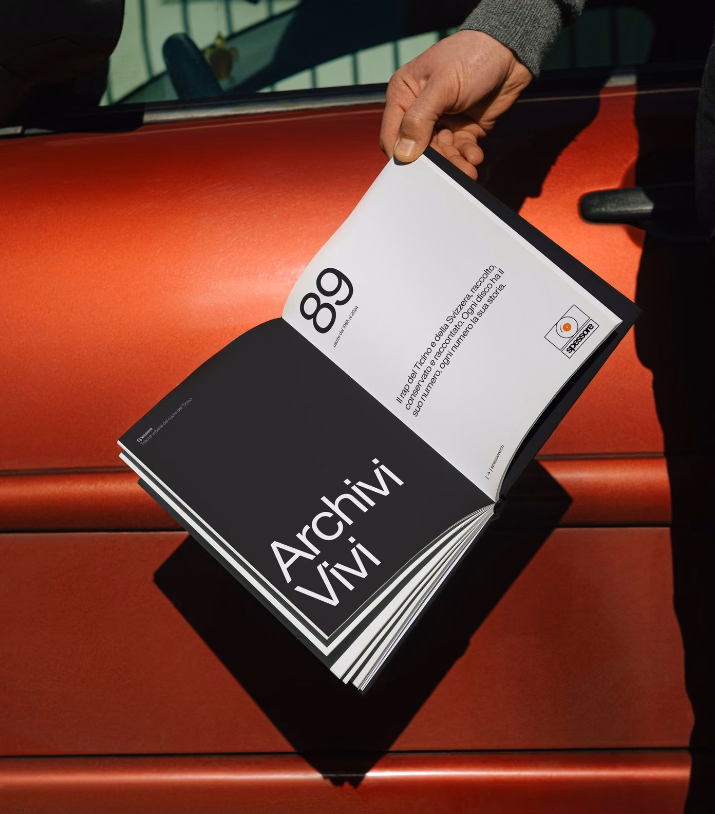 Archivi Vivi, the Spessore book, opened against a red car: 89 releases from 1995 to 2024